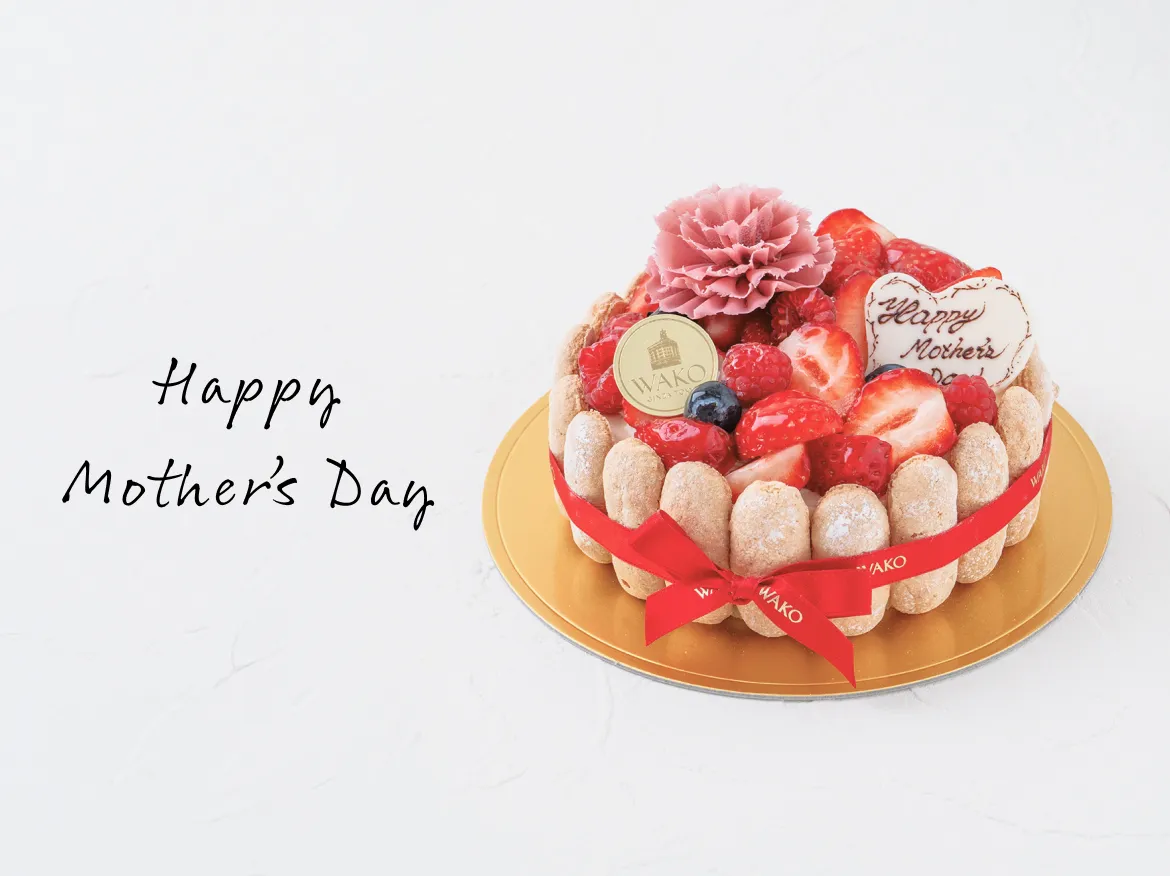 赤のリボンが巻かれた華やかで大きなケーキ「シャルロット フレーズ」の隣にHappy Mothers Dayが添えられている