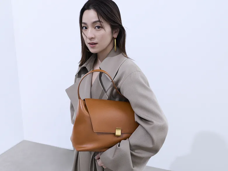 中村アンが新商品であるSUIHA くるみ色のトップハンドルバッグを持ち、こちらを見て立っている様子