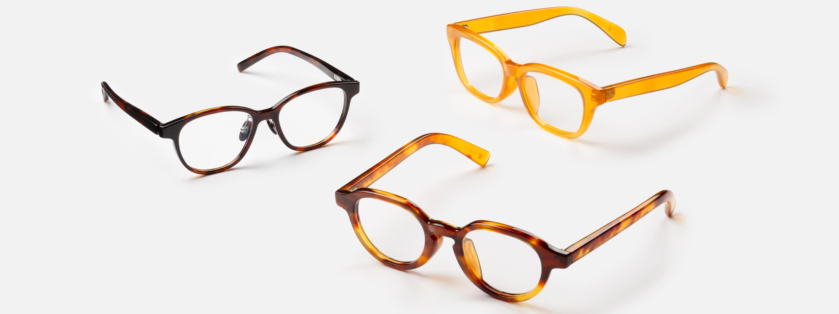 色と形が異なる3つのアイウェア（メガネ）が白い床に置かれている様子